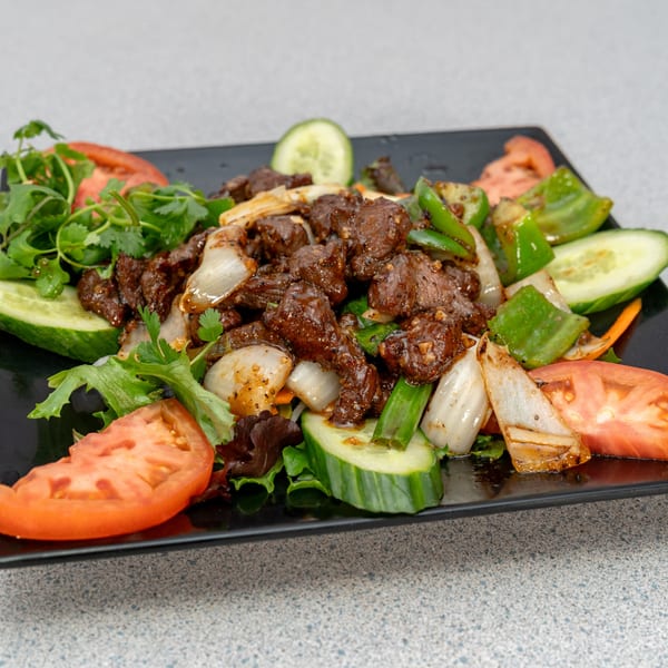 Vietnamese shaking beef (Bo Luc Lac) with bell peppers, onions, tomatoes, cucumbers, and cilantro.