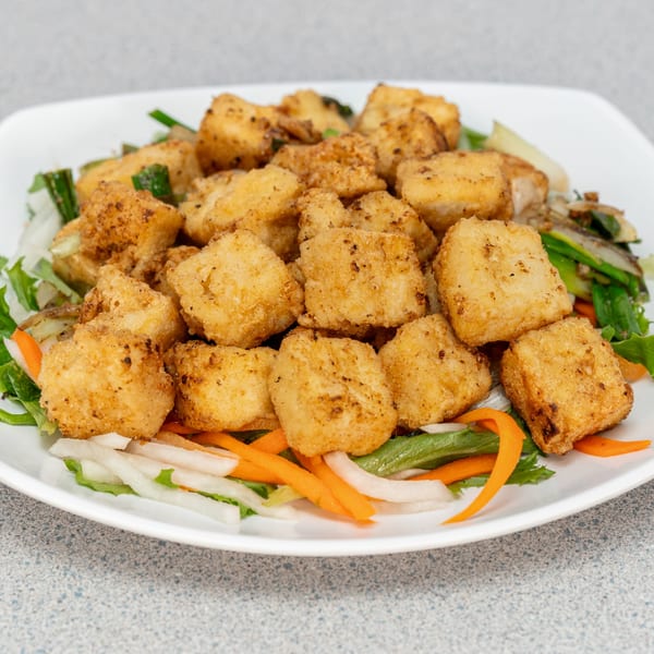 Crispy fried tofu cubes seasoned with pepper, served on a bed of fresh lettuce, carrots, and daikon.