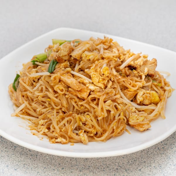 A white plate filled with Vietnamese Pad See Ew noodles, chicken, bean sprouts, and green onions.